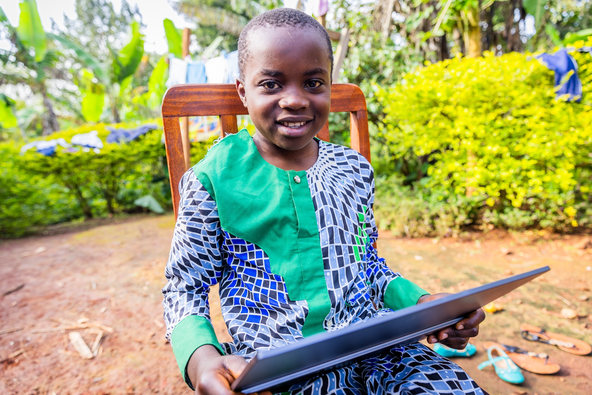 Happy African child sitting on a chair and holding his tablet. Education concept